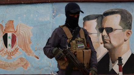 Ein Mitglied von HTS vor einem Bild von Bashar Assad. 