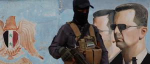 Ein Mitglied von HTS vor einem Bild von Bashar Assad. 