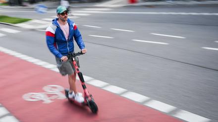 Ein Mann ist mit einem einem E-Scooter auf einem Fahrradweg unterwegs.