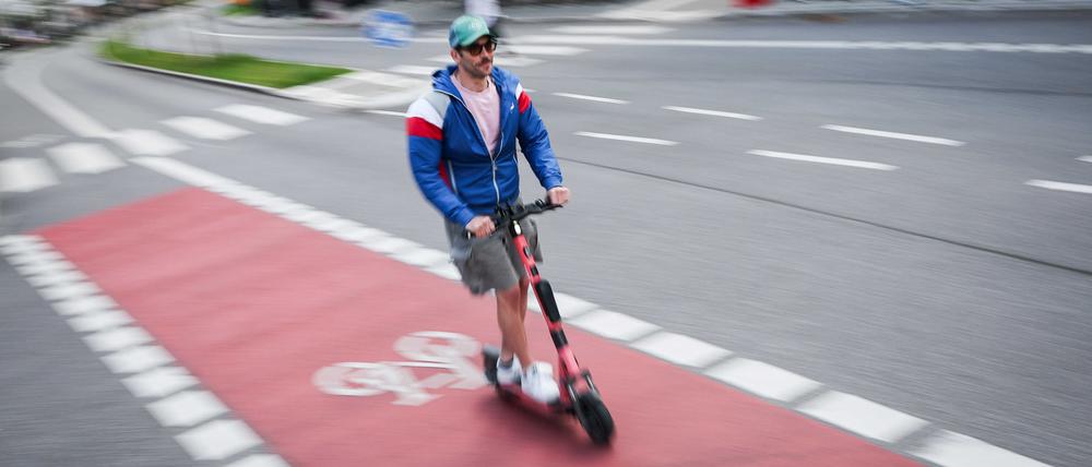 Ein Mann ist mit einem einem E-Scooter auf einem Fahrradweg unterwegs.