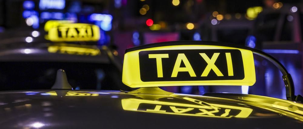 Ein Taxi mit beleuchtetem Taxischild wartet in einer Schlange von Taxis auf Fahrgäste.