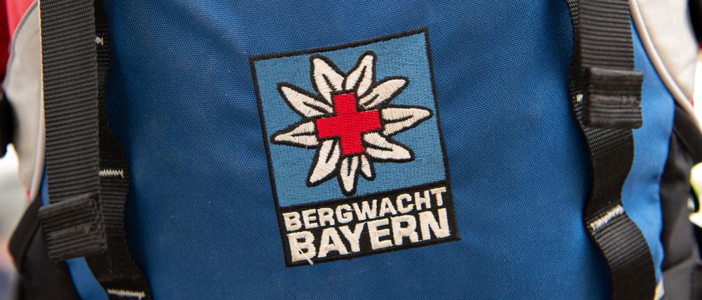 Das Logo der Bergwacht ist an einem Rucksack zu sehen. Bei Oberstdorf musste die Bergwacht nun einen Mann retten, der ohne richtige Ausrüstung und Erfahrung zwei Nächte in den Bergen verbrachte. (Archivfoto-Illustration)