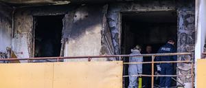 Ermittler der Kriminalpolizei stehen in einer ausgebrannten Wohnung in einem Mehrfamilienhaus.