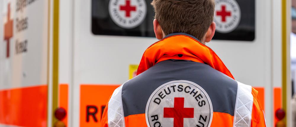 Ein Sanitäter vom Deutschen Roten Kreuz vor einem Krankenwagen.
