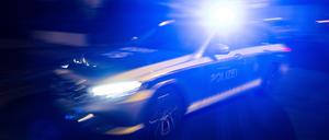 Ein Polizeifahrzeug fährt mit Blaulicht an einem Gebäude vorbei. 