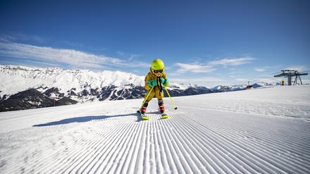 Ein Kind fährt Ski. Es trägt einen Helm.