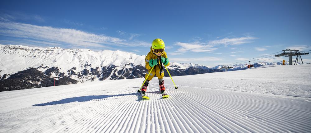 Ein Kind fährt Ski. Es trägt einen Helm.