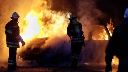 Feuerwehrmänner der Berliner Feuerwehr löschen ein brennendes Auto. (Symbolbild)
