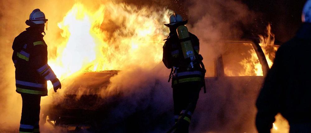 Feuerwehrmänner der Berliner Feuerwehr löschen ein brennendes Auto. (Symbolbild)