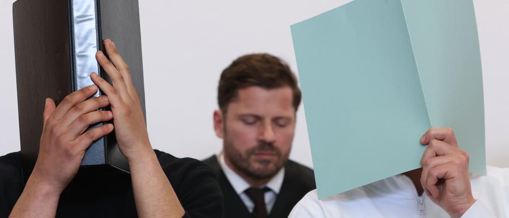 Der Hauptangeklagte (r) sitzt in einem Gerichtssaal neben weiteren Angeklagten vor Rechtsanwalt Harald Stehr (M) auf der Anklagebank. Der Mann wurde wegen eines Böllerwurfs mit zwölf Verletzten zu einer Gefängnisstrafe verurteilt, das Urteil ist nun rechtskräftig. (Archivbild)