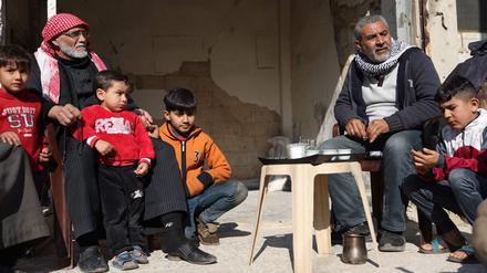 Nachbarn sitzen vor ihren zerstörten Häusern in Homs zusammen.
