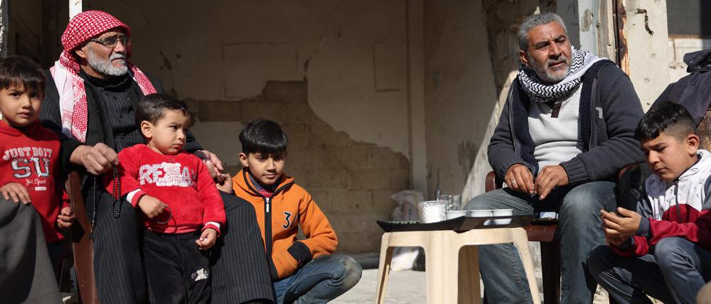 Nachbarn sitzen vor ihren zerstörten Häusern in Homs zusammen.