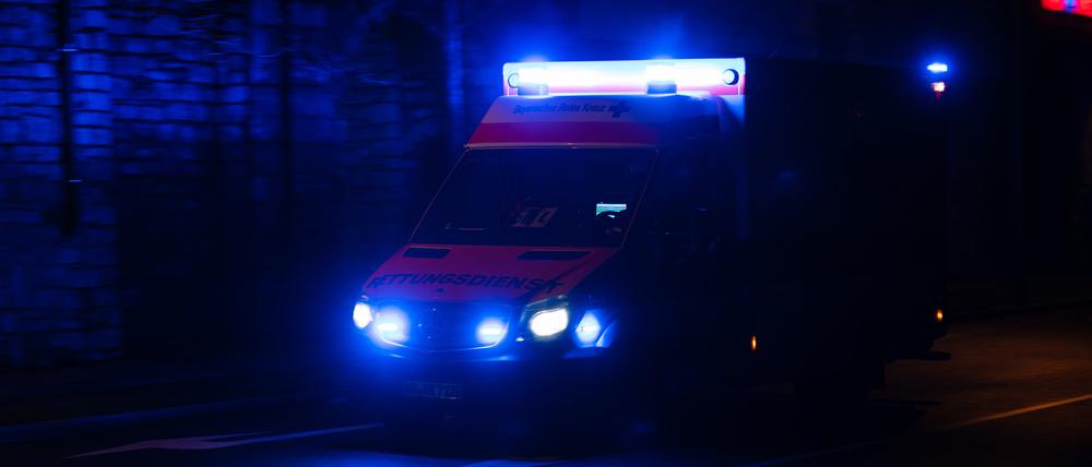 Ein Krankenwagen fährt nachts mit Blaulicht durch eine Straße. (Symbolbild)