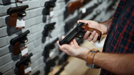Man holds handgun in gun shop. Male person buying pistol for security in weapon store, selfdefence and sport shooting hobby