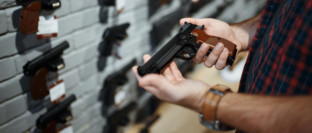 Man holds handgun in gun shop. Male person buying pistol for security in weapon store, selfdefence and sport shooting hobby