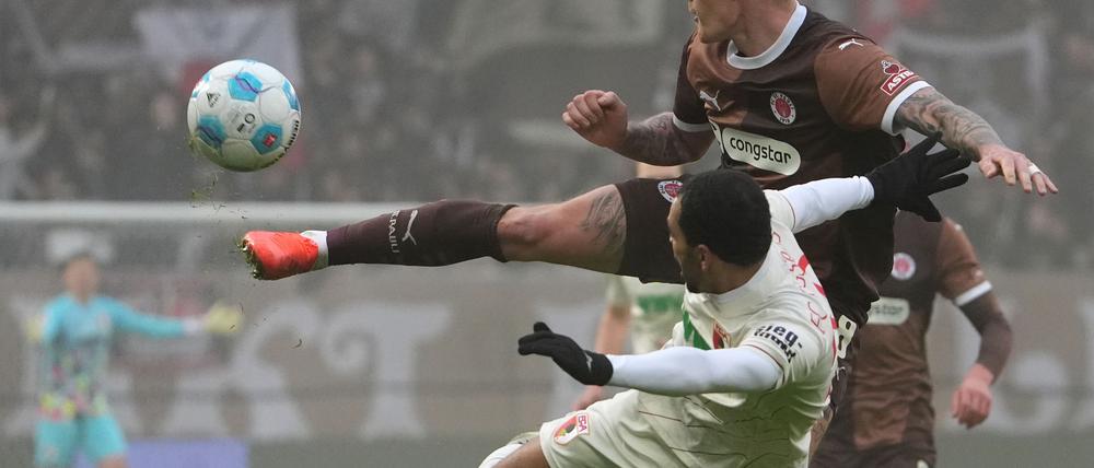  St. Paulis Eric Smith (r) und Augsburgs Alexis Claude-Maurice kämpfen um den Ball.