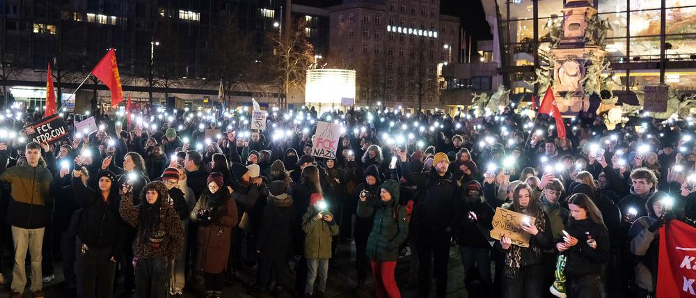 Zahlreiche Menschen versammeln sich bei einer Demonstration gegen die Migrationspolitik der CDU auf dem Augustusplatz und leuchten mit ihren Smartphones.