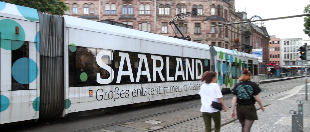 Eine Tram mit Werbeaufschrift „Saarland – Großes entsteht immer im Kleinen“ fährt vor dem Rathaus in der Innenstadt von Saarbrücken.