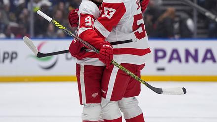 Moritz Seider (re.) feiert mit Alex DeBrincat den Siegtreffer in Vancouver - den sechsten Sieg in Serie mit den Detroit Red Wings.
