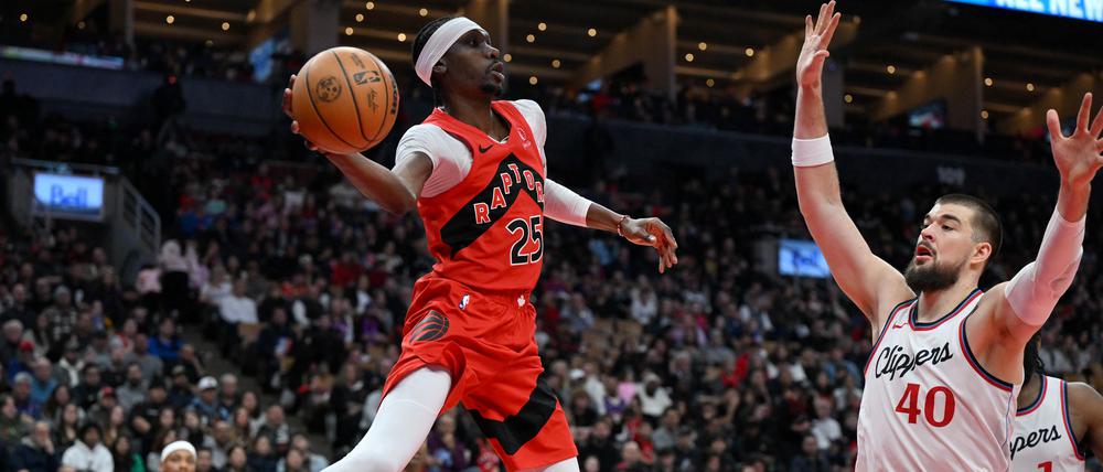 Feb 2, 2025; Toronto, Ontario, CAN;  Toronto Raptors forward Chris Boucher (25) passes the ball over Los Angeles Clippers center Ivica Zubac (40) in the first half at Scotiabank Arena. 