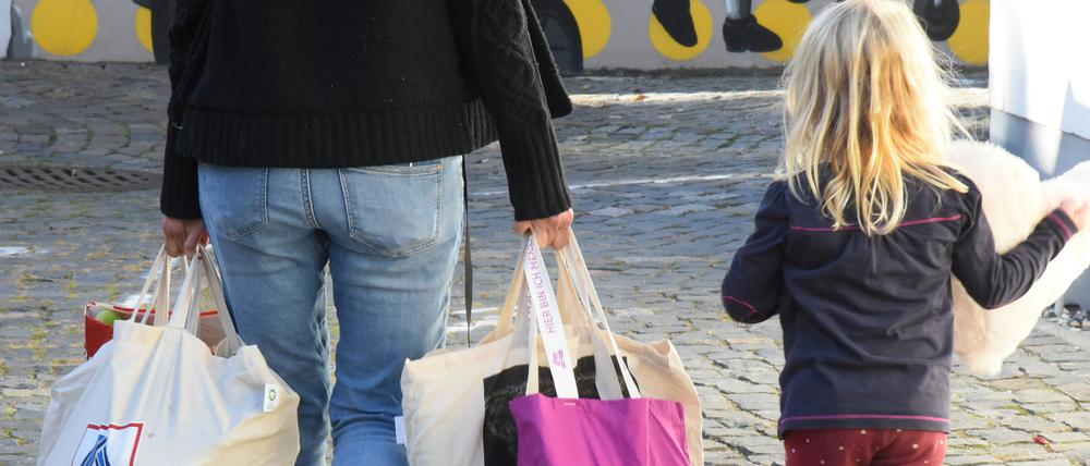 An einer Ausgabestelle einer Tafel gehen eine Frau und ein Kind mit gespendeten Lebensmitteln nach Hause.