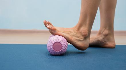 Eine Frau nutzt eine Massagerolle für ihren Fuß