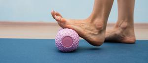 Eine Frau nutzt eine Massagerolle für ihren Fuß