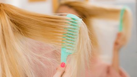 Eine Frau kämmt ihre langen blonden Haare.