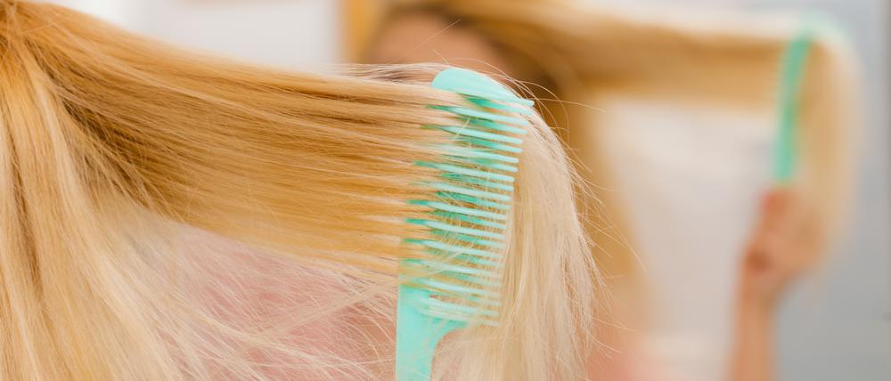 Eine Frau kämmt ihre langen blonden Haare.