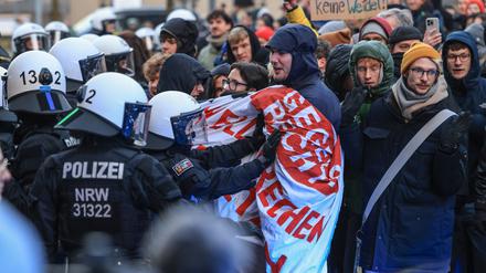 Polizisten schieben an der Uniklinik in Köln Demonstranten beiseite, um die Abfahrt von CDU-Chef Merz zu ermöglichen. Die beiden CDU-Politiker Merz und Wüst haben im Rahmen des Wahlkampfes die Krebsklinik in Köln besucht. 