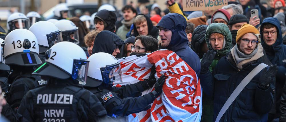 Polizisten schieben an der Uniklinik in Köln Demonstranten beiseite, um die Abfahrt von CDU-Chef Merz zu ermöglichen. Die beiden CDU-Politiker Merz und Wüst haben im Rahmen des Wahlkampfes die Krebsklinik in Köln besucht. 