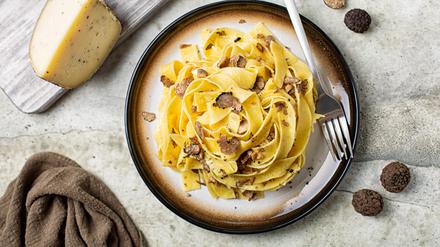 Top view of truffle fettuccine with mushrooms, long egg pasta. Italian first course made with hard cheese and butter. Ingredients.