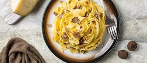 Top view of truffle fettuccine with mushrooms, long egg pasta. Italian first course made with hard cheese and butter. Ingredients.