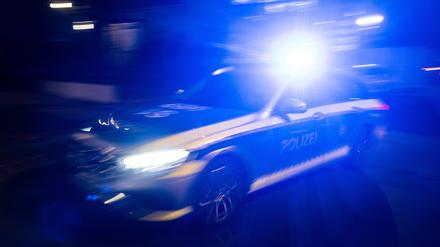 Ein Polizeifahrzeug fährt nachts mit Blaulicht an einem Gebäude vorbei. (Symbolbild)