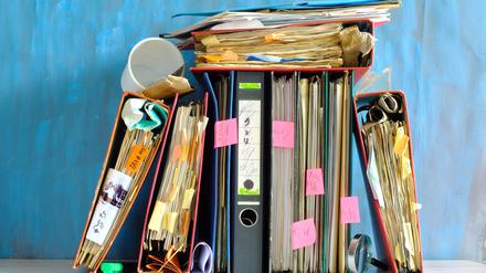 Chaotische Anordnung von überfüllten Aktenordnern mit Merkzetteln (Symbolbild). Dass in Deutschland so viel Bürokratie anfällt, hat auch damit zu tun, dass Vorschriften handhabbar, fair und klagesicher sein müssen. 