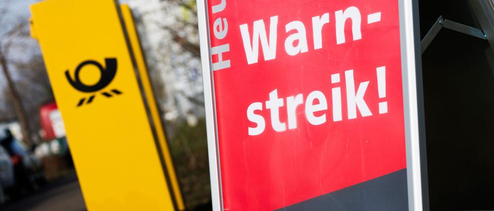 Ein Warnstreik-Schild bei einem Post-Standort, daneben ein Briefkasten - im Ringen um einen Tarifabschluss haben Tausende Postler erneut die Arbeit niedergelegt.