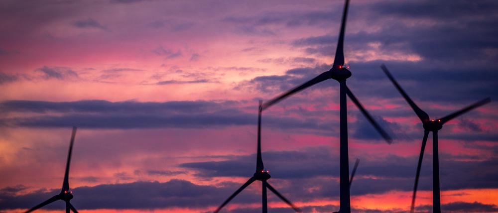 Die Rotoren von Windkraftanlagen drehen sich nach Sonnenuntergang in einem Windpark. 