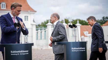 Christian Lindner (FDP, l), damals Bundesminister der Finanzen, Bundeskanzler Olaf Scholz (SPD, M) und Robert Habeck (Bündnis 90/Die Grünen), Bundesminister für Wirtschaft und Klimaschutz, verlassen zum Ende der Halbzeit-Klausur des Bundeskabinetts vor Schloss Meseberg die Pressekonferenz.