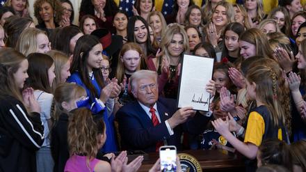 Donald Trump inszeniert sich mit Mädchen und Frauen, während er das Dekret unterzeichnet.