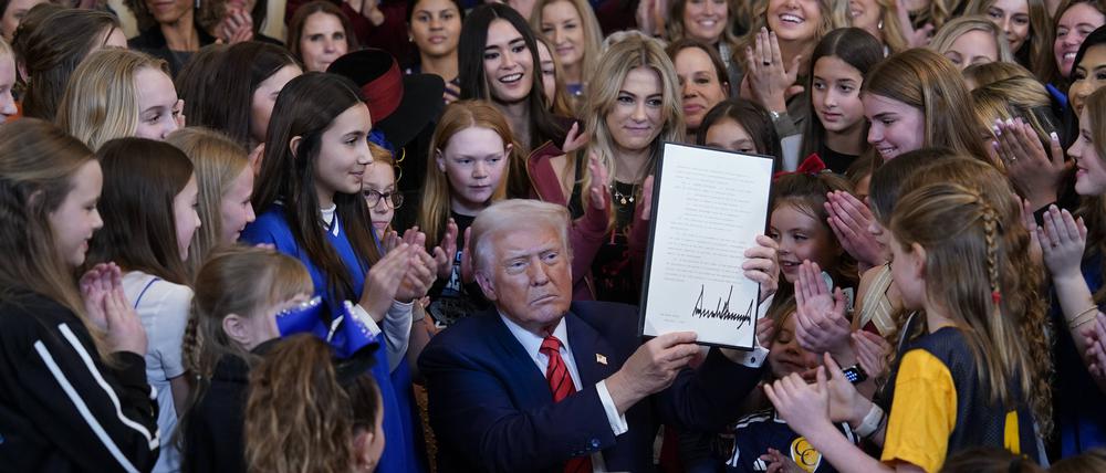 Donald Trump inszeniert sich mit Mädchen und Frauen, während er das Dekret unterzeichnet.