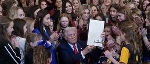 Donald Trump inszeniert sich mit Mädchen und Frauen, während er das Dekret unterzeichnet.