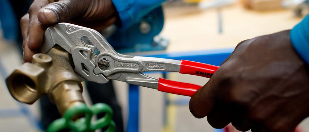 Ein Flüchtling arbeitet in der Lernwerkstatt auf dem Gelände der Bayernkaserne unter professioneller Anleitung an einem Werkstück.