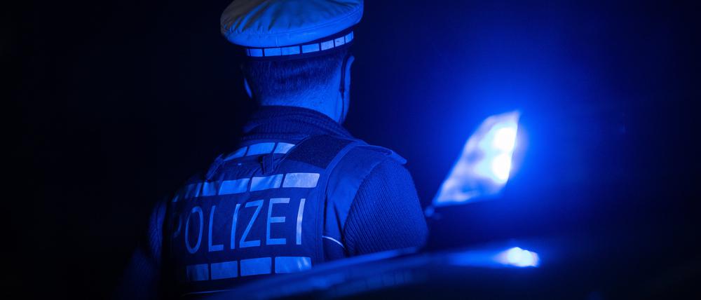Ein Polizist steht neben einem Polizeifahrzeug. 
