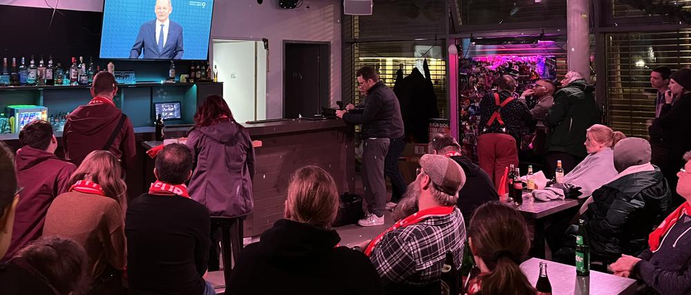 SPD-Unterstützer sehen Olaf Scholz (SPD) während eines Kanzlerduell-Redebeitrags in einer Bar in Berlin-Adlershof zu.
