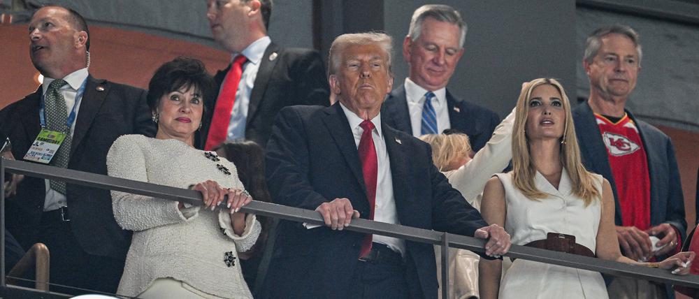 Der Präsident steht. Donald Trump schaut zu.