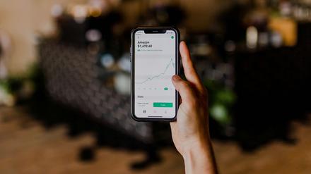 Eine Hand hält ein Smartphone, auf dem ein einbrechender Amazon-Chart zu sehen ist.