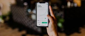 Eine Hand hält ein Smartphone, auf dem ein einbrechender Amazon-Chart zu sehen ist.