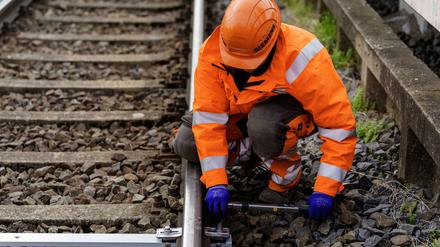Ein Siemens-Mitarbeiter zeigt wie eine Balise, technische Einrichtung zum Übertragen von Informationen an das Schienenfahrzeug, im Gleis montiert wird. 