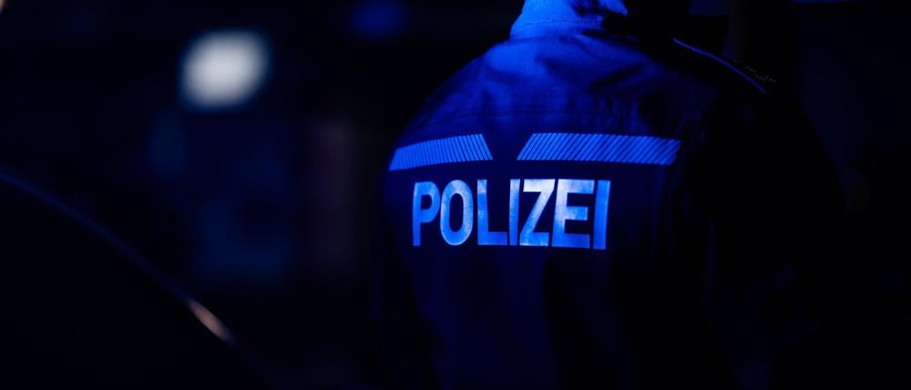 Ein Polizist steht neben einem Polizeiauto.