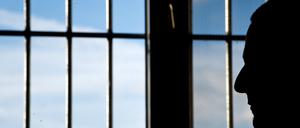 Ein Gefängnisinsasse sitzt in einer Justizvollzugsanstalt vor einem vergitterten Fenster.